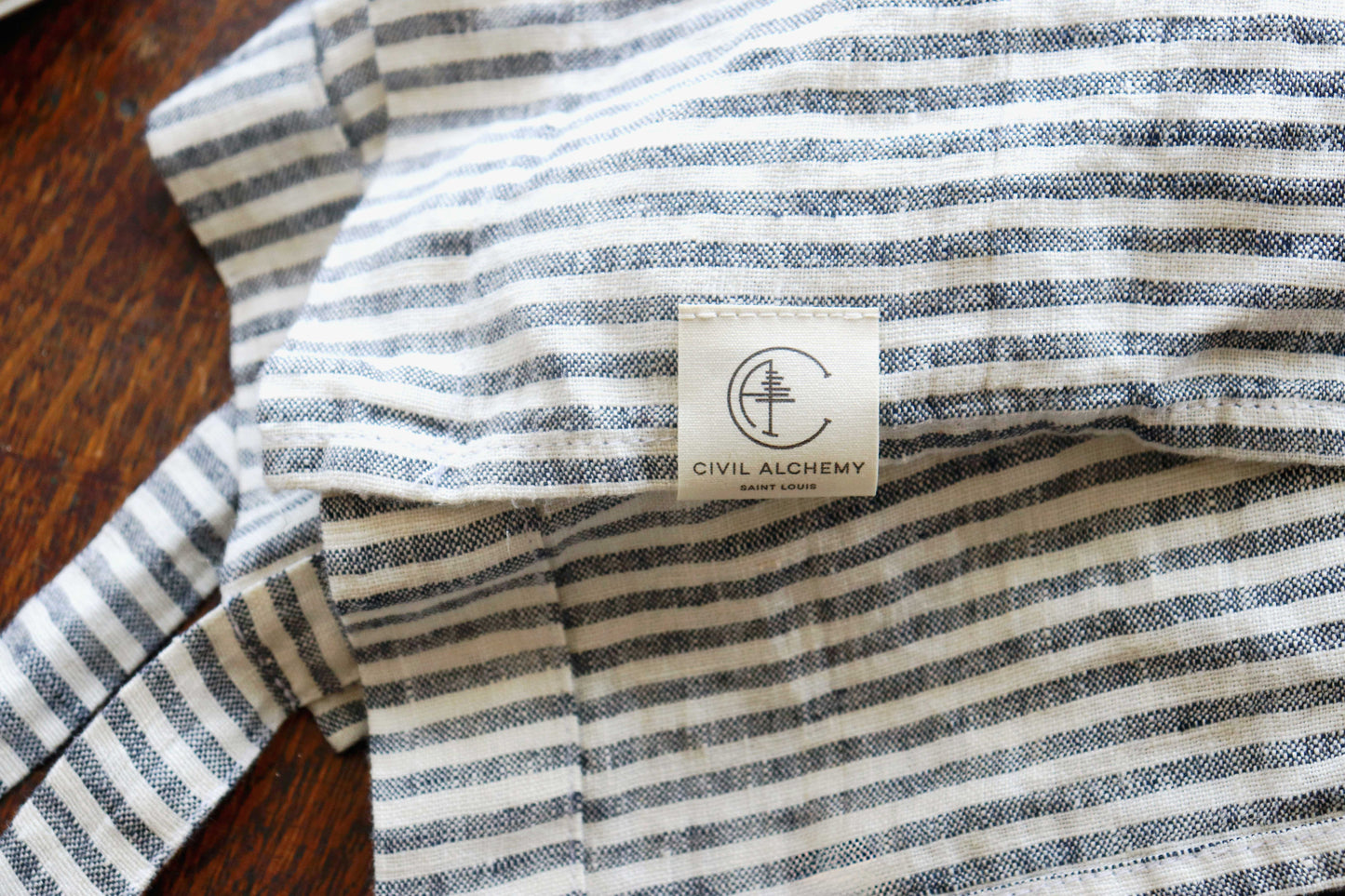 Striped apron with a visible brand label on a wooden surface