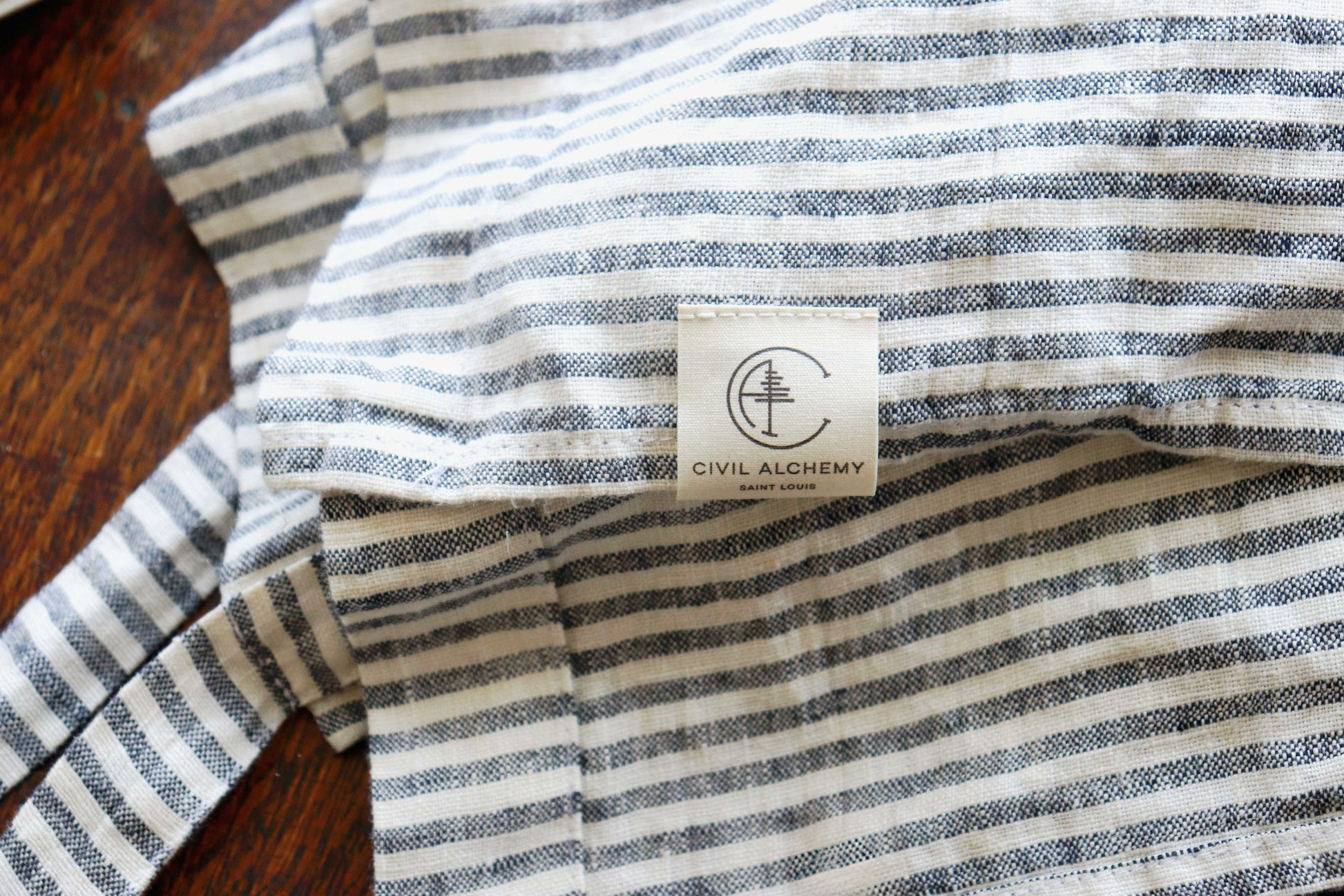 Striped apron with a visible brand label on a wooden surface
