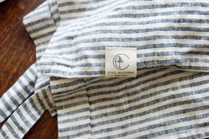 Striped apron with a visible brand label on a wooden surface