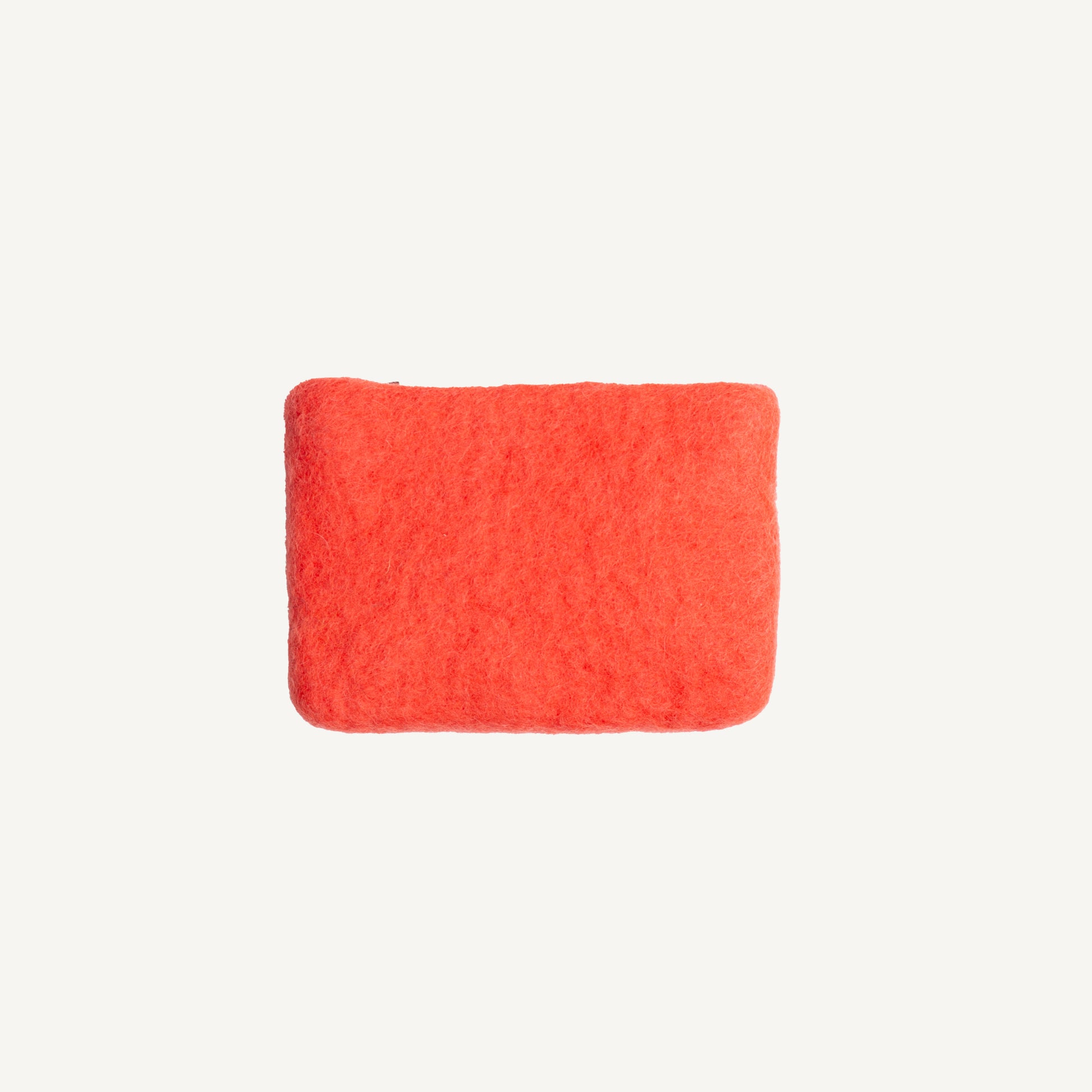 A solid poppy wool coin pouch with a brass zipper, hand-felted by artisans in Nepal.