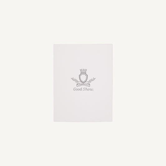 A white letterpress congratulations card with a small decorative emblem and text on the front, placed on a clear background.