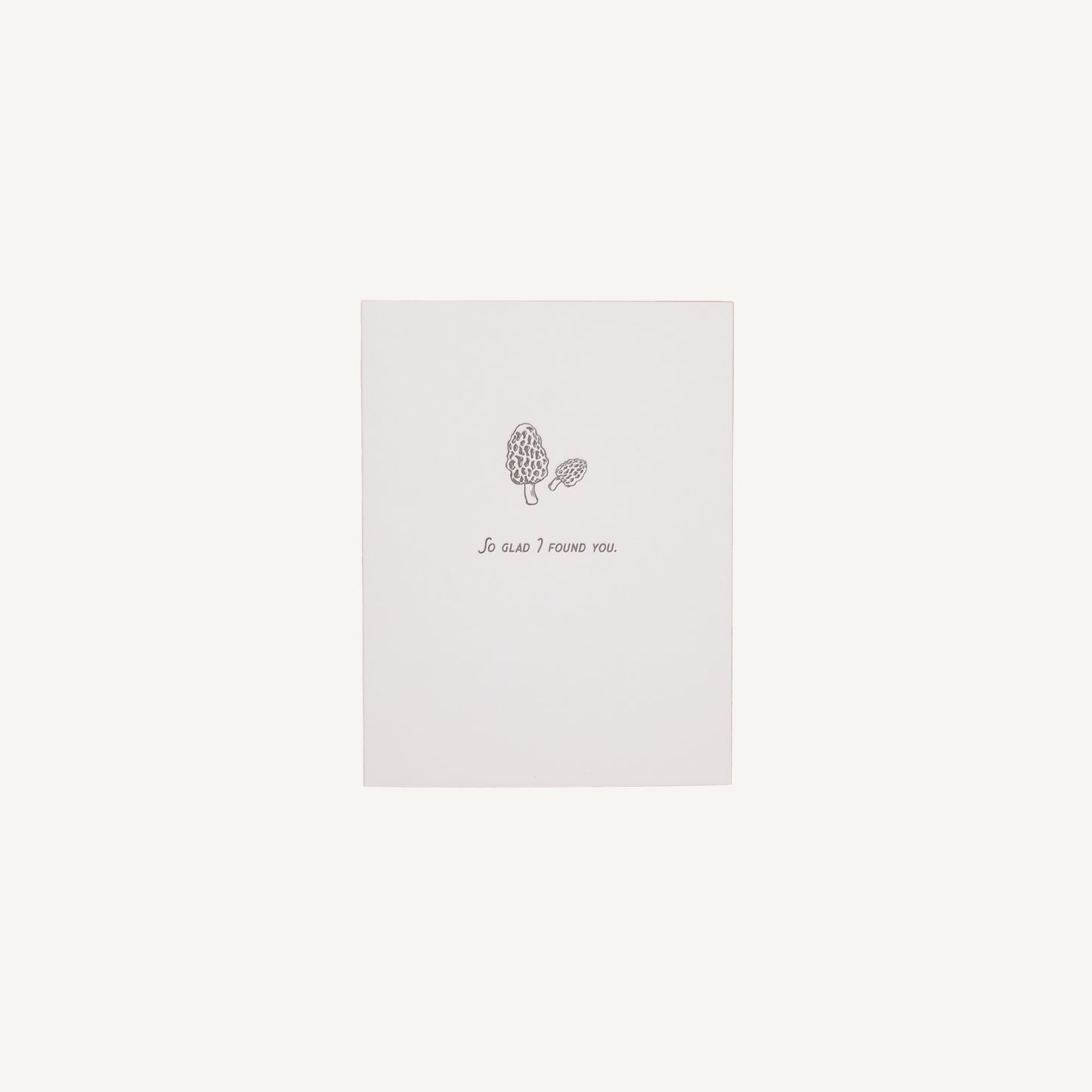 A white letterpress card with a floral design and the text 'So Glad I Found You' on it, placed against a plain background.