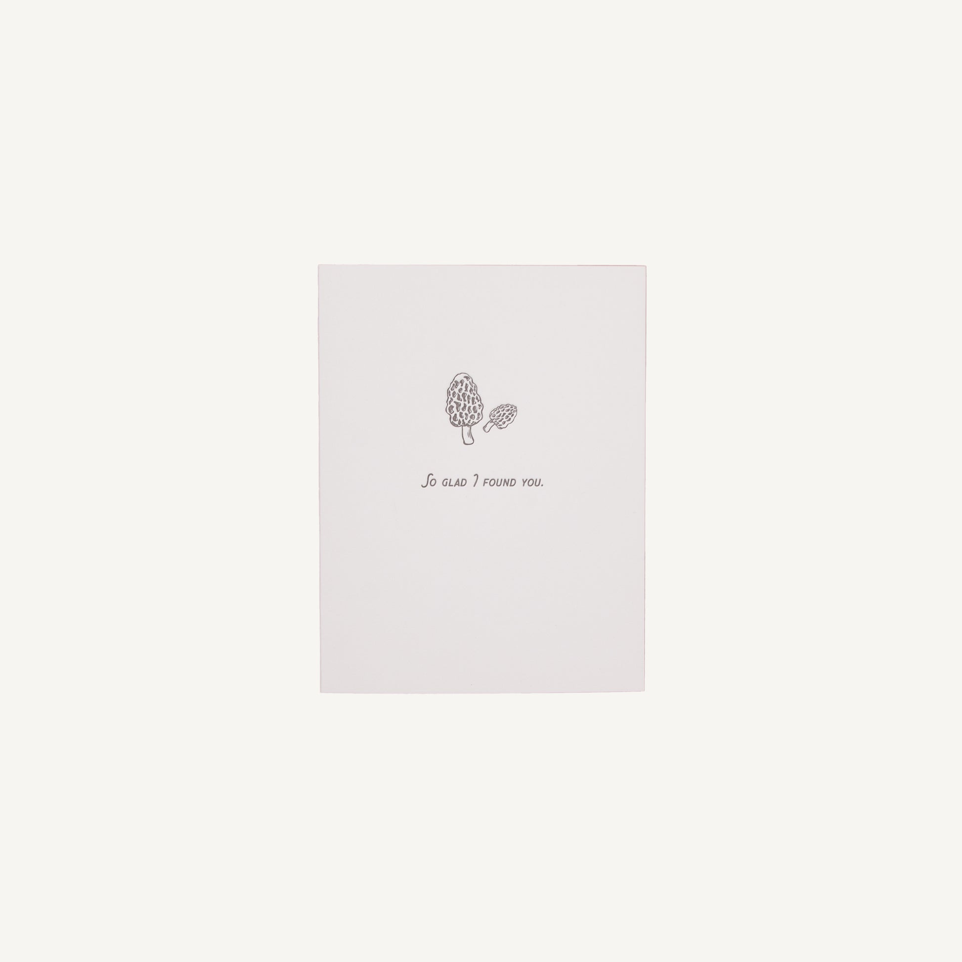 A white letterpress card with a floral design and the text 'So Glad I Found You' on it, placed against a plain background.