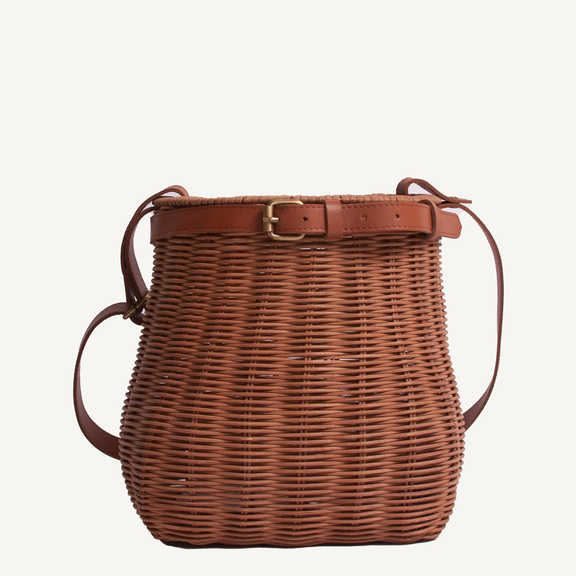 A brown wicker foraging basket with brass hardware and adjustable straps.