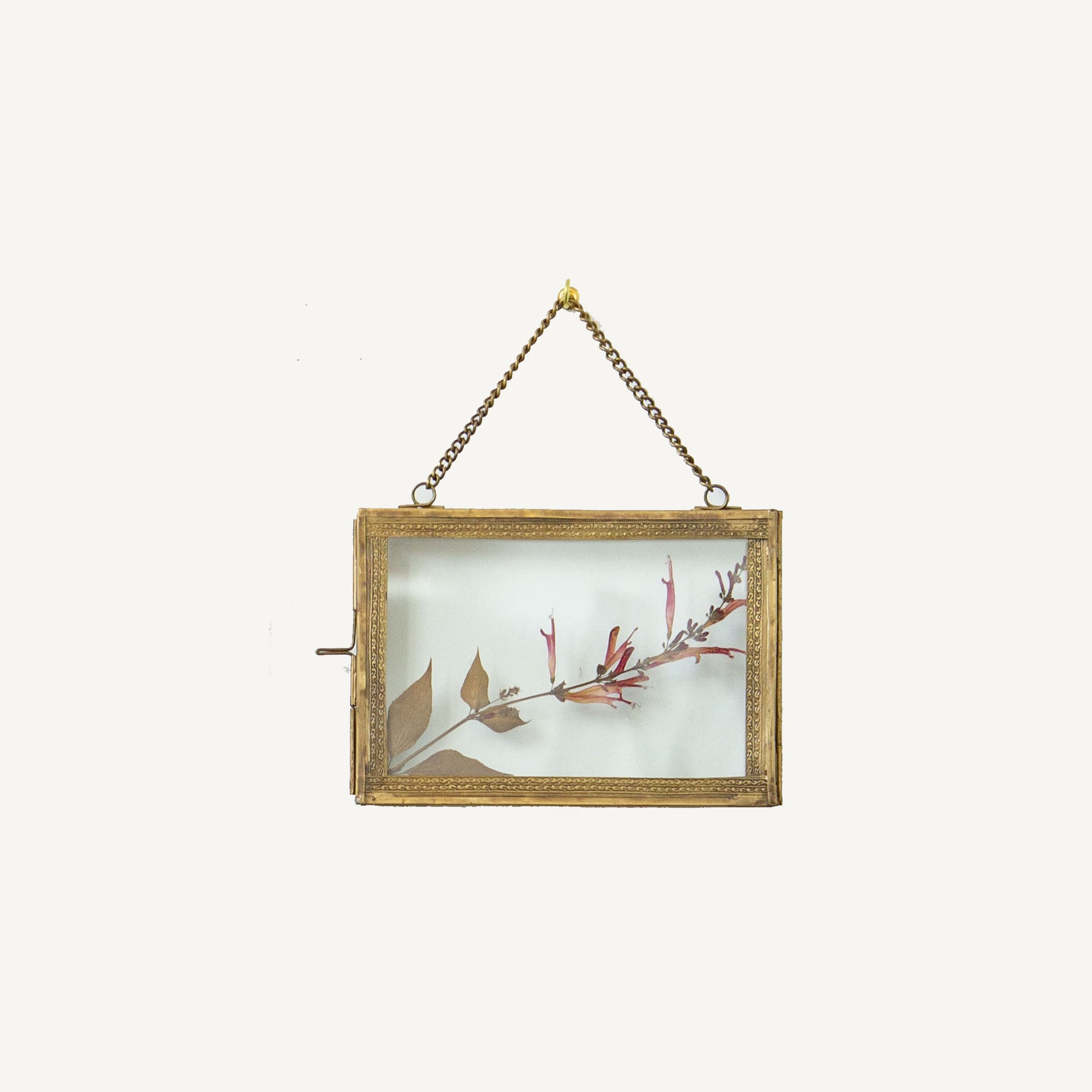 A brass hanging photo frame with a 5x7 dimension, featuring a floral design within the frame, displayed against a plain background.