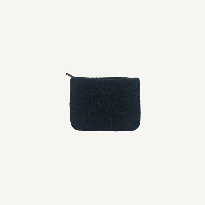 A solid black wool coin pouch with a brass zipper, hand-felted by artisans in Nepal.
