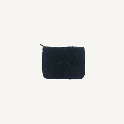 A solid black wool coin pouch with a brass zipper, hand-felted by artisans in Nepal.