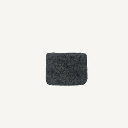 A solid black wool coin pouch with a brass zipper, hand-felted by artisans in Nepal.